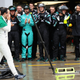 Felipe Massa covers his eyes and tears with his hands as he walks down the pit lane at Autodromo José Carlos Pace during the 2016 Formula 1 Brazilian Grand Prix. His last home race before retiring, he is wearing a Brazilian flag draped over his shoulders, and the Mercedes pit crew is applauding him.